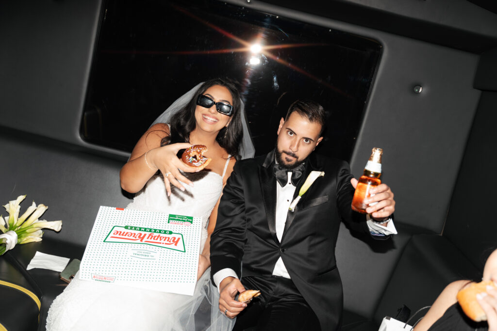 Newlyweds eating doughnuts in limousine.