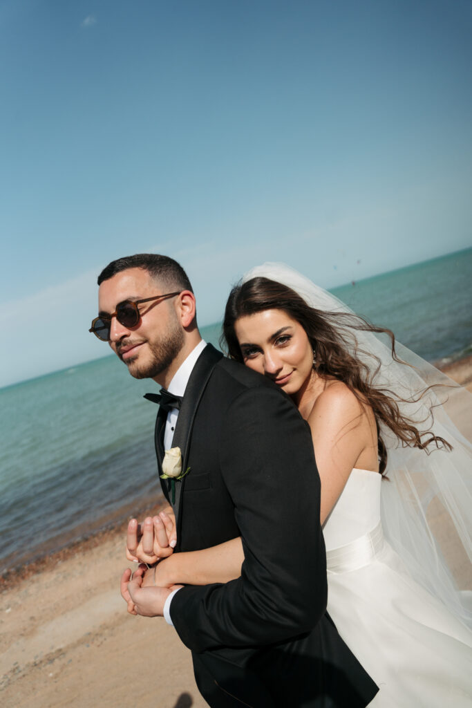 Newlyweds embracing on a beach. | Gabys Films