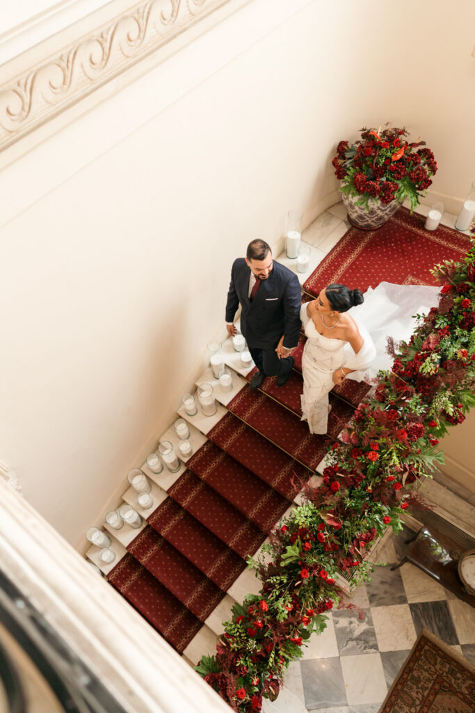 Couple walking down floral staircase. | Gabys Films